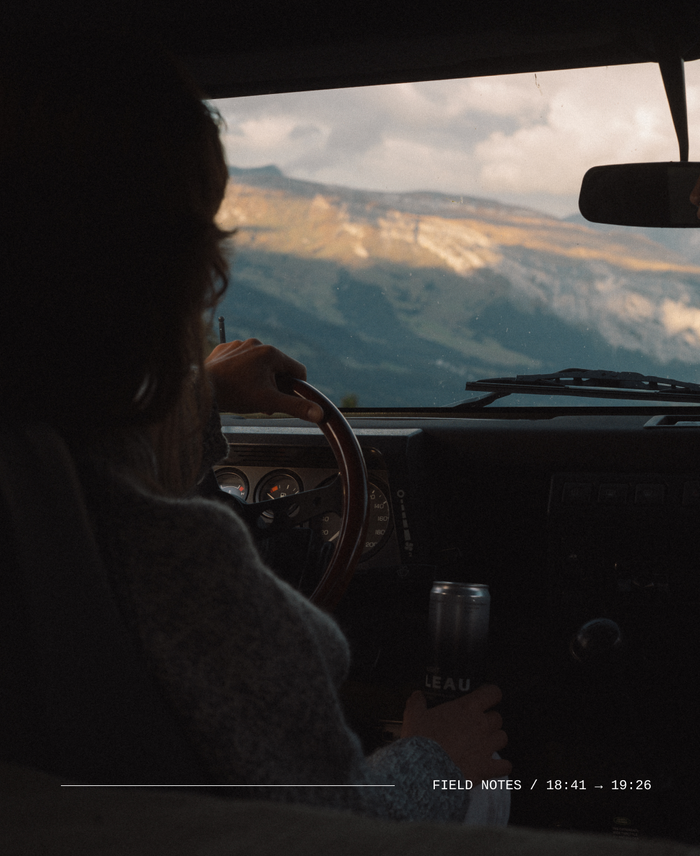 A view of the top of a mountain from the back of a car through the front window. 